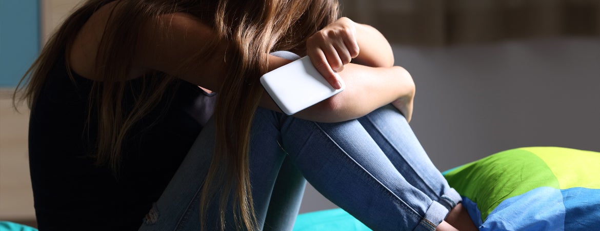 Hazing Information A person cries on their bed, their head pulled to their knees.