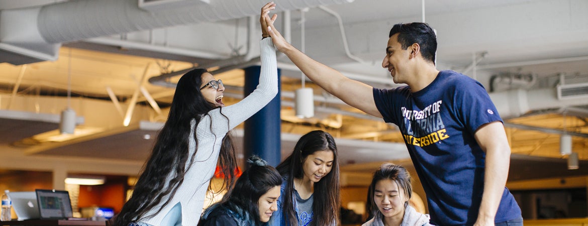 Two UCR students in a study group high-five each other. 